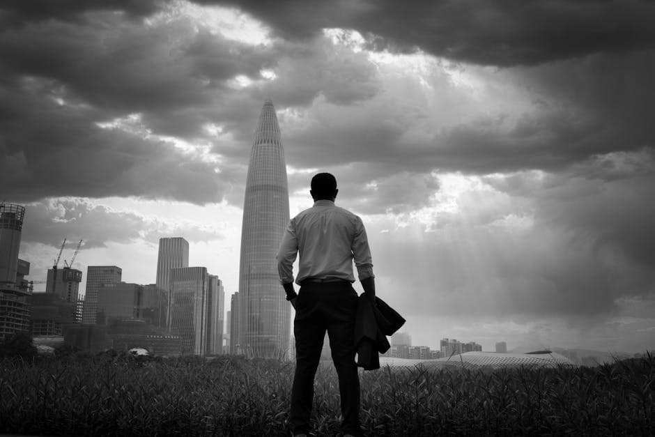 Silhouette of a man facing a dramatic city skyline under stormy clouds.