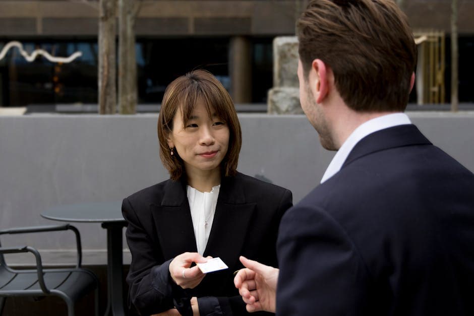 Two business professionals having a meeting outdoors, exchanging business cards.