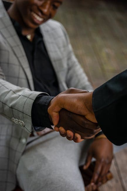Close-up of a handshake between two businessmen in a modern professional setting.