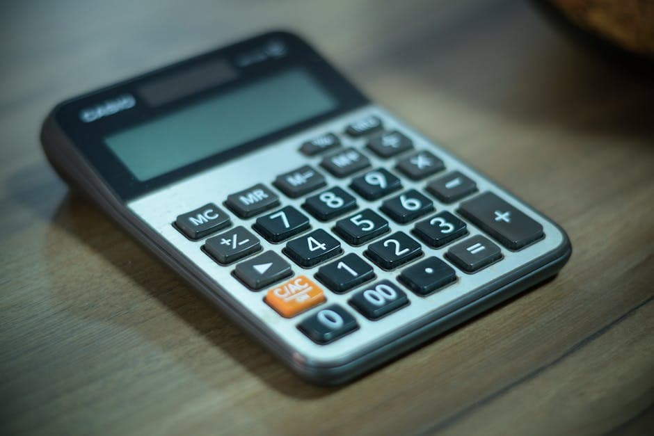Digital calculator resting on a wooden table, selective focus.