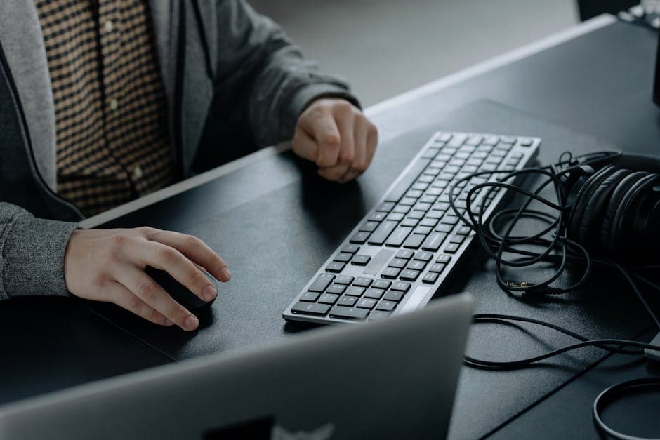 Close-up of a person typing on a sleek computer keyboard in a modern workspace setting.