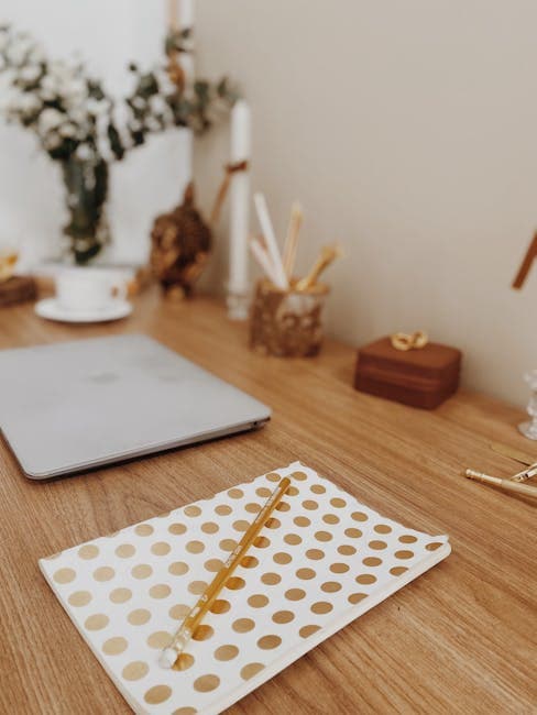 Elegant workspace featuring polka dot notebook, gold accents, and decor elements on a wooden desk.