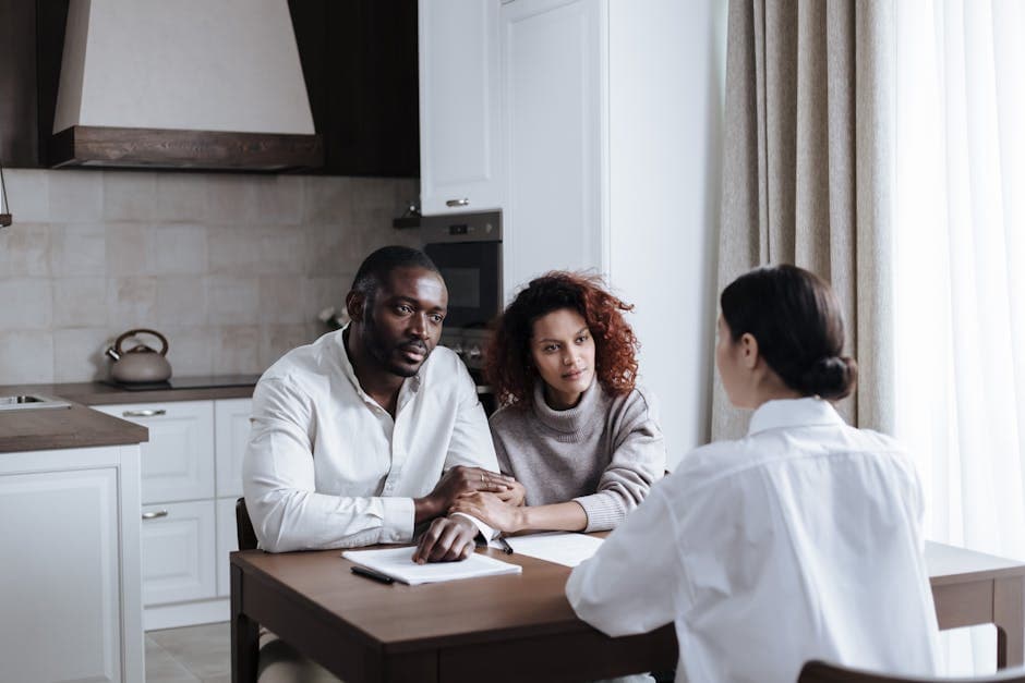 A couple discusses adoption with a social worker in a modern kitchen setting.