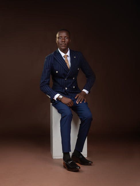 Professional man in a tailored suit sitting confidently in a studio portrait.