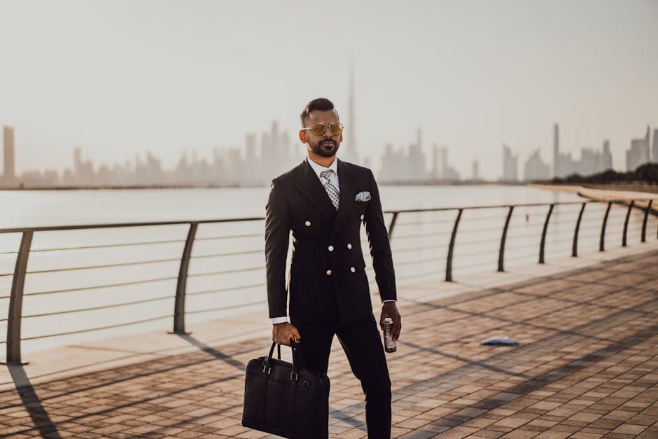 Stylish businessman in Dubai with city skyline in background, holding briefcase.