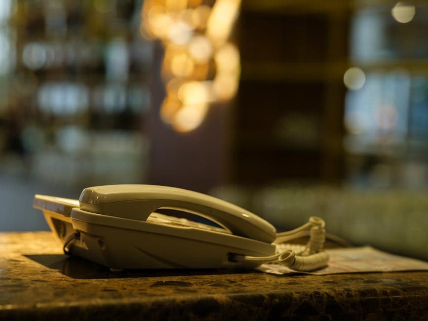 Close-up of a vintage landline phone on a marble counter in a blurred indoor setting.